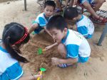 Bé lớp lá chơi với cát